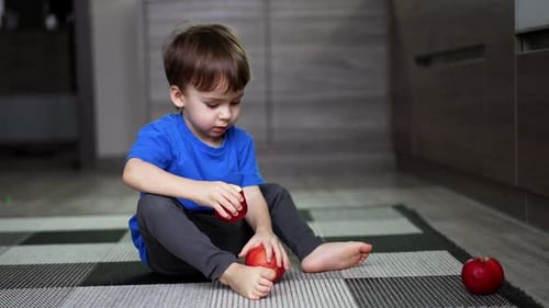 Boy Plays With Red Apples Indoors
