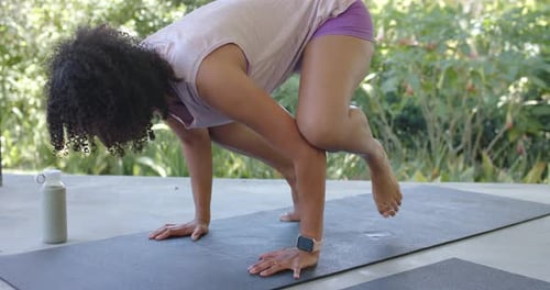 Une femme place les mains sur un tapis de yoga sur la terrasse, déplace du poids, soulève les pieds, cherche l'équilibre des bras