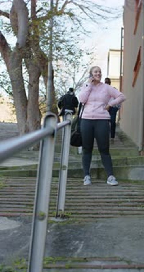 Vidéo verticale : smartphone qui sonne, femme qui monte les marches, répond à un appel et ajuste la sangle du sac