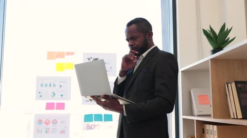 Professional Man Reviews Data on Laptop in Office