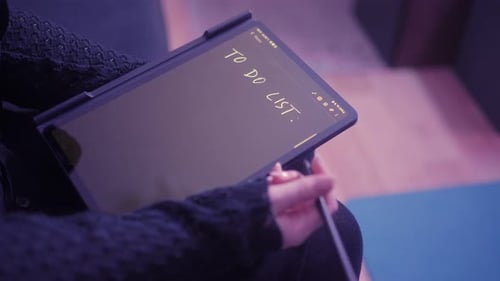 Young woman is thinking about a list of things to do, which she is writing on a tablet. Consideratio