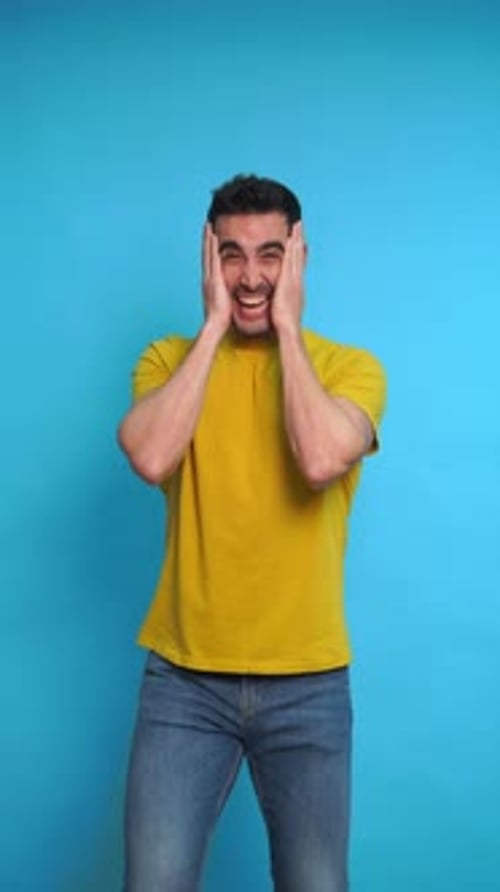 Excited Young Man with Hands on Cheeks in Studio