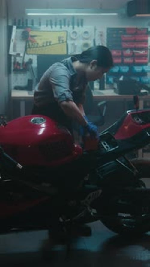 Une femme prend la batterie de la moto, la place dans le compartiment et reconnecte les bornes