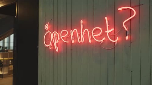 Une enseigne au néon sur laquelle on peut lire « open » ? « traduit par « ouverture » ? « monté sur un mur vert foncé, ajoutant une touche