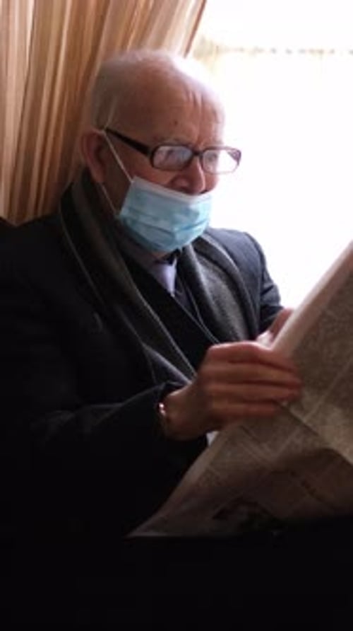Elderly Man Calmly Reads Newspaper During Quarantine Finding Peace at Home