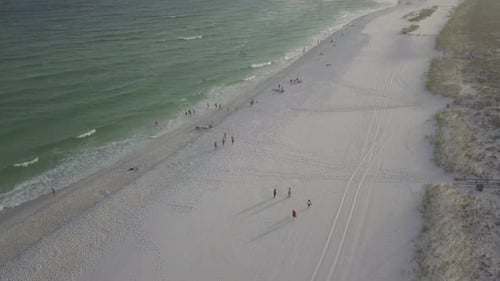Aerial Flight Over Sandy Beach, Waves, And Tourists On Cloudy Day - drone shot