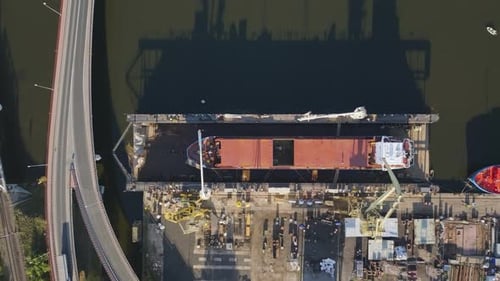 Aerial view of industrial shipyard with cranes and docked vessels in harbor