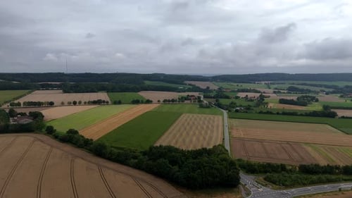 Dark clouds sky over colored cultivated farm fields and mountains in back. Aerial panorama view. Sum