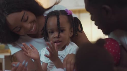 Happy family gathers around toddler at birthday party