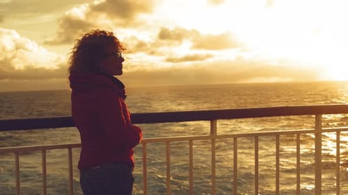 Side view of tourist enjoying sunset light on the ocean standing on the ferry boat deck in travel