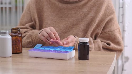 Woman Organizes Pills into Pill Organizer at Home