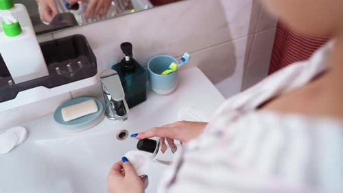 Woman Applies Toner to Cotton Round in Bathroom