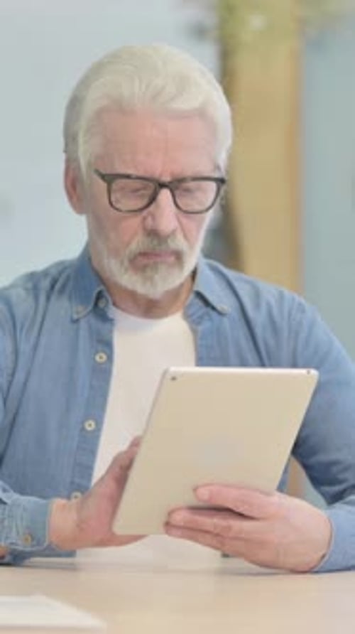 Old Man Working on Digital Tablet, vertical video