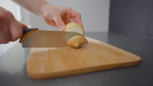 Slicing An Onion With Sharp Knife On Board
