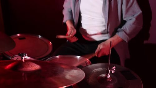 Man playing drums with drumsticks in studio, closeup