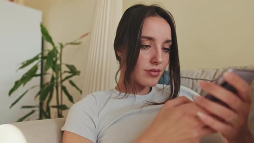 Close-up of young woman using phone while sitting on sofa at home