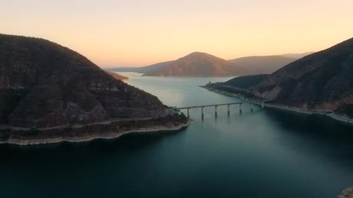 Aerial drone flying over a lake, water dam, with mountains at sunrise. Beautifull dreamy landscape
