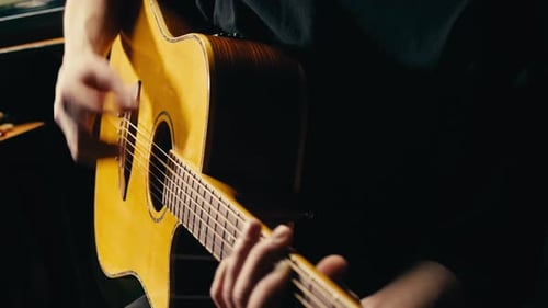 Young Musican Man Checking Strings of Acoustic Guitar Closeup Male Guitarist Tuning Sound of Musical