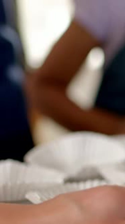 Vertical video: Hand moving adult and youth placing cups in muffin tray to bake at home dark apron