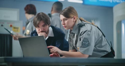 Airport Security Checkpoint Two Diverse TSA Workers Using Laptop Discussing Security Issues