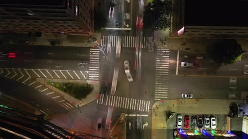 A top down, aerial view of a NYC intersection at night. The camera is stationary and tilted straight