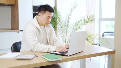 Young Adult Typing on Laptop in Home Office