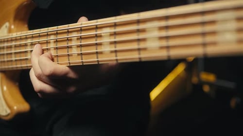 Young Musician Man Sitting and Playing the Electric Acoustic Guitar Among Music Equipment in Studio