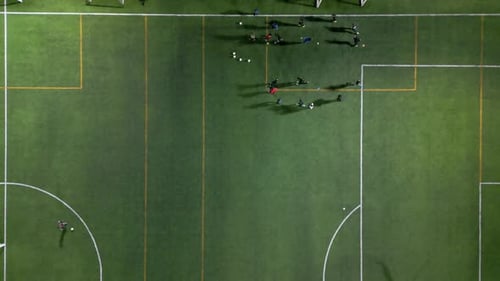 Topdown View of a Football Training Session on a Green Field Under Artificial Lights with Players