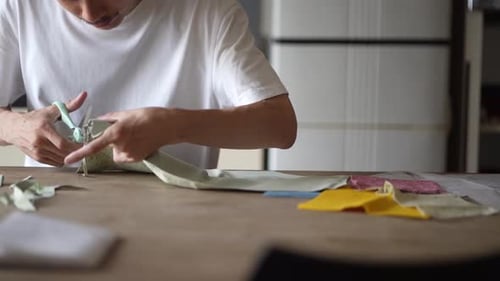 Young Adult Cutting Fabric with Scissors at Table