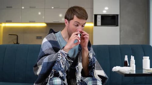 Man Using Nasal Spray While Sick at Home