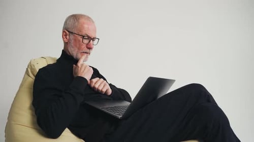 Senior Man Using Laptop in Chair