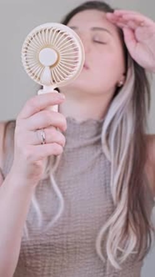 Woman Cooling Off with a Portable Handheld Fan
