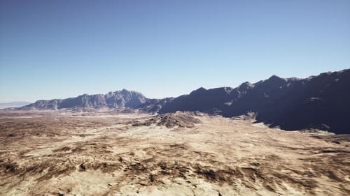 Broad Barren Terrain with Silhouetted Mountain Range Under Clear Sky