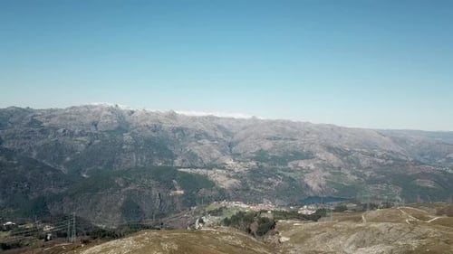 Luftbild über grüne Natur und Hügel, in Richtung steiler Berge und strahlendes Sonnenlicht. Drohnenschuss mit