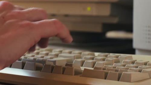 Hombre trabajando y jugando en una computadora retro, ingeniero de TI con una computadora antigua en casa usando una vieja