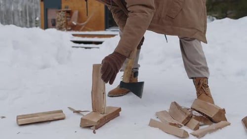 Adult Chopping Wood Outdoors in Winter