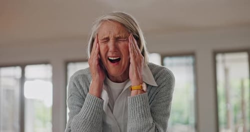 Senior Woman Massaging Temples in Home