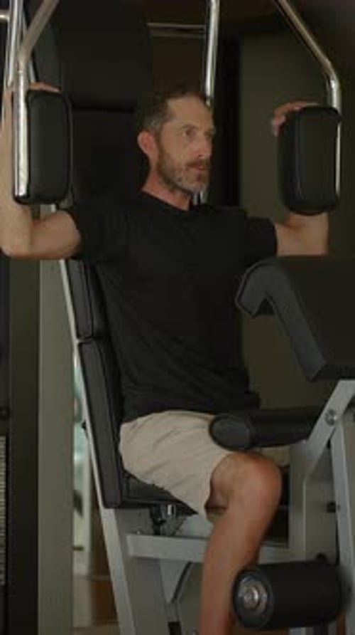 A Man is Exercising Vigorously on a Fitness Machine at the Gym Improving His Health and Strength
