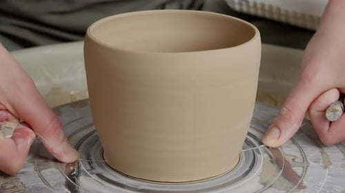 Craftsperson Cuts Clay Pot from Pottery Wheel