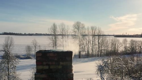 Close up of cottage brick chimney with smoke come out, snowy winter landscape