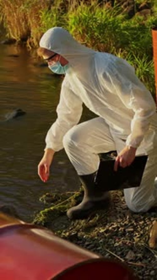 Researcher in Protective Suit Examining River Water