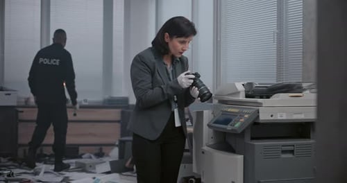 Woman Examines Camera at Office Crime Scene