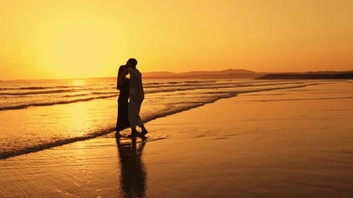 A Couple Standing on the Beach at Sunset