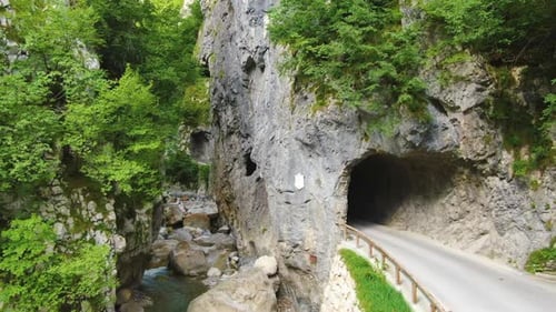 Traffic road with tunnel and Shallow river between the stones. Wild and untouched nature. Aerial foo