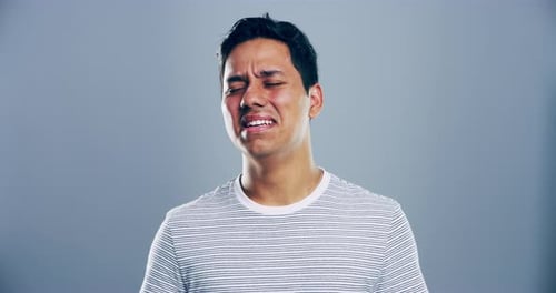 4k video footage of a young man crying against a grey background