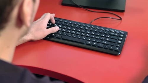 Person Typing on Keyboard at Red Desk