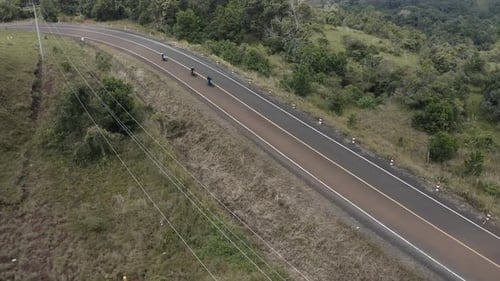 4k tracking Aerial shot over a group of motorcycle rider crossing a curve hill top road surrounding