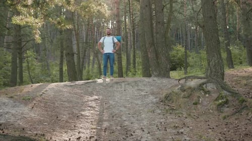 Smiling Handsome Young Man Hiker Standing in the Forest Look Around Happy at Sunlight Nature Alone