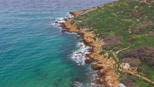 Aerial view of rocky coastlines and green hills, Malta.