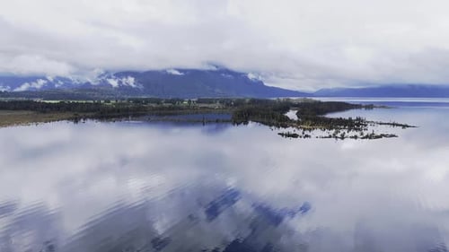 Serene Clouds Drift Over Tranquil Lake with Mountain Reflections in Timelapse Nature